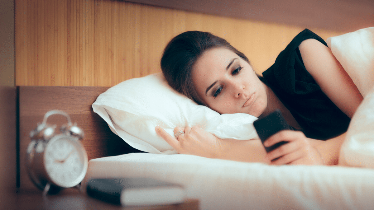 unhappy lady laying in bed texting