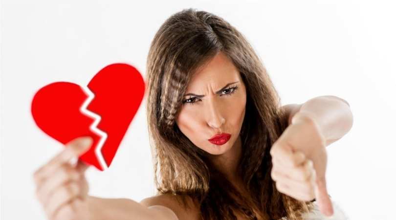 woman holding broken heart with thumbs down