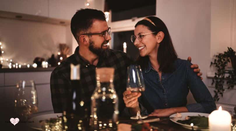 couple holding wine glasses talking to each other