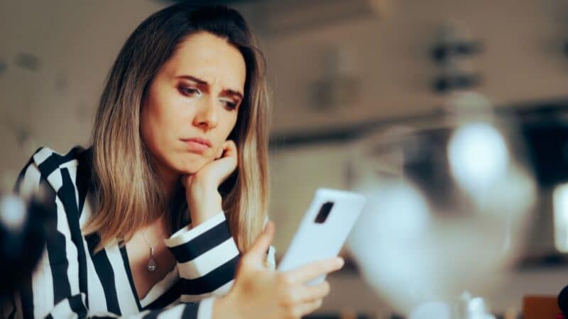 woman holding phone and sad