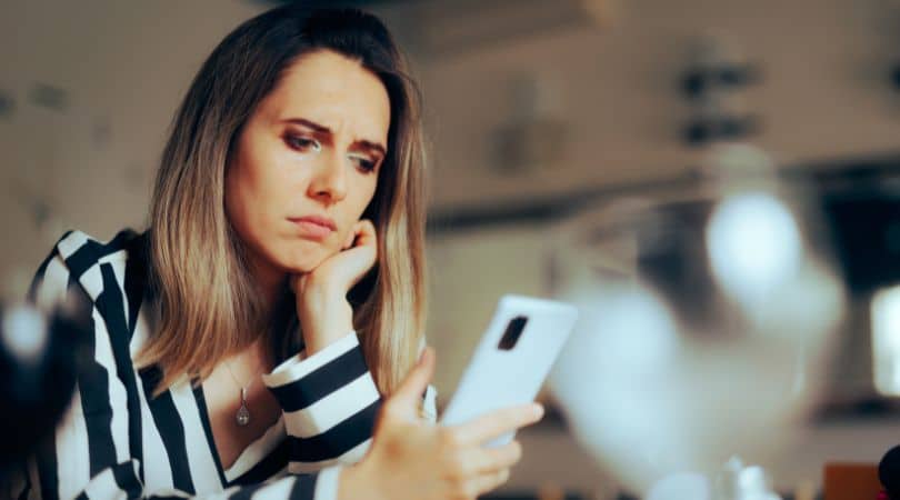 woman holding phone and sad