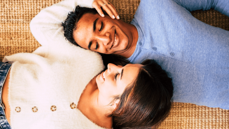 couple holding each other laying down on the ground.