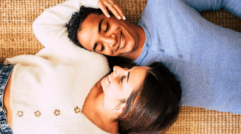 couple holding each other laying down on the ground.