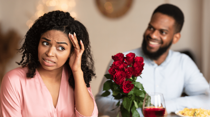 Couple on date and the man is holding flowers while the lady cringes on the date