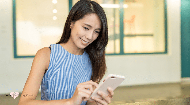 woman looking at her smart phone while smiling