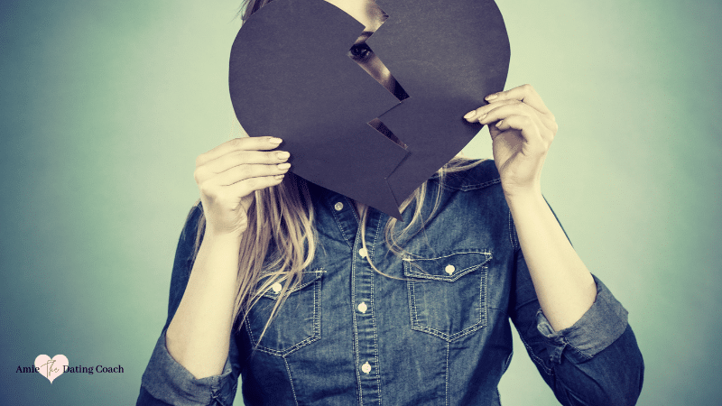 Woman holding a black heart that is broken
